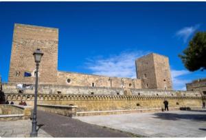 a person standing in front of a large brick building at Trulli & Case Fichi 3 in Bari