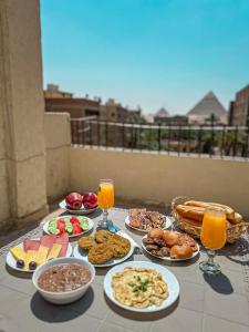 una mesa con platos de comida y vasos de jugo de naranja en The Pyramid Vault View INN, en El Cairo