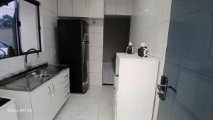 a small kitchen with a refrigerator and a sink at aconchegante com piscina e churrasqueira, pertinho da praia" in Itapoa