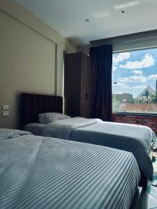 Dos camas en una habitación de hotel con ventana. en The Pyramid Vault View INN, en El Cairo