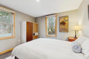 a bedroom with a white bed and two windows at The River House in West Wardsboro