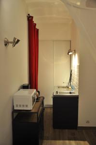 a room with a microwave and a red curtain at location studio meublé avec jardin in Sorgues