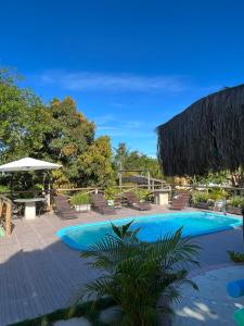 a swimming pool with chairs and an umbrella at Pousada Luar de Caraíva in Caraíva