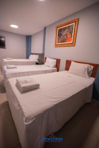 two beds in a hotel room with towels on them at Hotel JORGE CHAVEZ in Trujillo