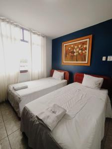 a room with two beds and a painting on the wall at Hotel JORGE CHAVEZ in Trujillo +10 photos