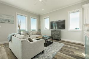 ein Wohnzimmer mit Sofa und Fernseher in der Unterkunft Luxury Gulf Views Pool Exclusive Villa in Bolivar Peninsula