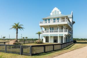 ein weißes Haus mit einem Zaun und Palmen in der Unterkunft Luxury Gulf Views Pool Exclusive Villa in Bolivar Peninsula