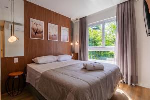 ein Schlafzimmer mit einem Bett und einem großen Fenster in der Unterkunft Rosa Edifício Bav in Gramado