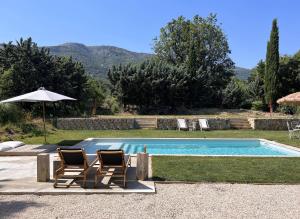 a swimming pool with two chairs and an umbrella at Villa Victoire - Mini villas avec terrasse privée in Vauvenargues