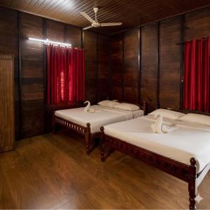 two beds in a room with red curtains at Karlad Lake Palace Waterfront Resort in Tariyod