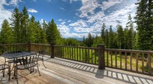 a patio with a table and chairs on a wooden deck at Challenger Cabin in Big Sky Mountain Village