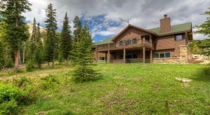 a large house on a grassy field in the woods at Challenger Cabin in Big Sky Mountain Village