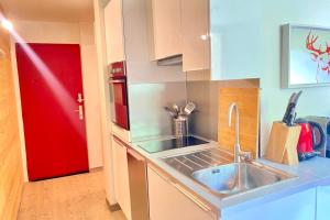 cocina con fregadero y puerta roja en Bright apartment near the slopes, en La Salle-les-Alpes