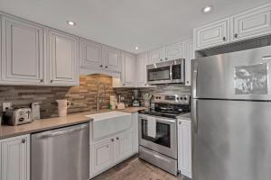 a kitchen with white cabinets and a stainless steel refrigerator at Island Winds East Condo 402 in Gulf Shores