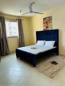 un letto con testiera blu in una stanza di Arjazz Homes a Mombasa