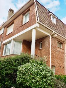 een rood bakstenen huis met een witte pilaar bij Charmante Villa 5 min de la plage et garage in Le Touquet-Paris-Plage