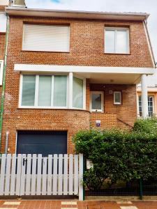 een stenen huis met een wit hek ervoor bij Charmante Villa 5 min de la plage et garage in Le Touquet-Paris-Plage