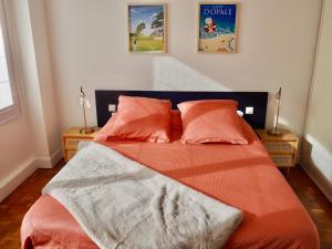 een slaapkamer met een bed met oranje lakens en 2 lampen bij Charmante Villa 5 min de la plage et garage in Le Touquet-Paris-Plage