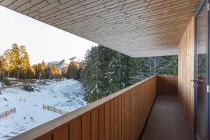a wooden balcony with a view of a snow covered forest at 1BR Apart In Kokhta Mitarbi in Bakuriani