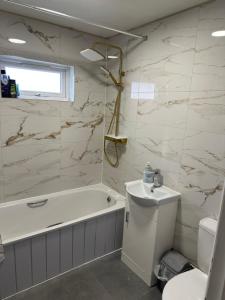 une salle de bain avec une baignoire, des toilettes et un lavabo dans l'établissement HP Wizards Corner Spacious 4 bed near Watford Junction, à Watford 11 autres photos