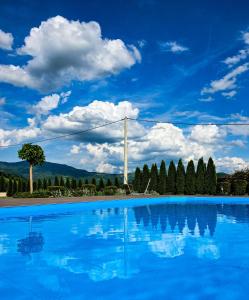 a blue swimming pool with a blue sky and clouds at Lane Apartmani - Terasa in Vrhpolje