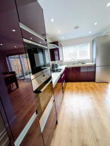 クルーにある3 bed cosy homeのウッドフロアの広いキッチン(ステンレス製の電化製品付)