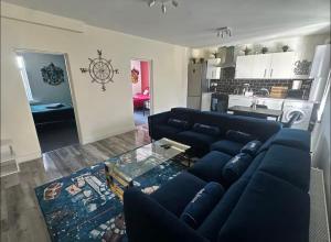 un salon avec un canapé bleu et une cuisine dans l'établissement HP Wizards Corner Spacious 4 bed near Watford Junction, à Watford