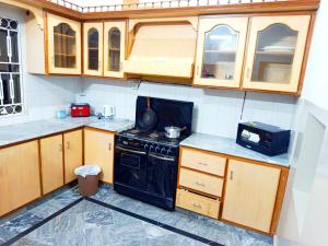 a kitchen with a black stove and wooden cabinets at Skyline Serenity Guest House in Rawalpindi