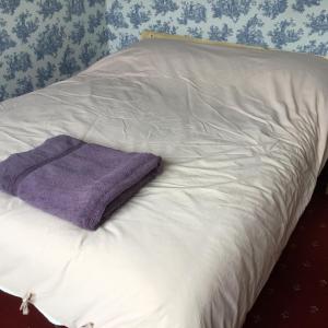 a white bed with a purple towel on it at Lowry House Hotel in Walsall in Birmingham