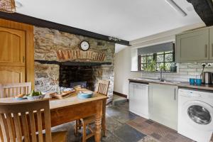 a kitchen with a table and a stone fireplace at Myrtle Grove in Saint Endellion
