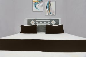 a bedroom with a large white bed with black pillows at SPOT ON Anmay in Phāphāmau +47 photos