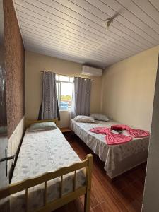 une chambre avec deux lits et une fenêtre dans l'établissement Pousada Fênix,com piscina -250 METROS DA PRAIA, à Pontal do Paraná 74 autres photos
