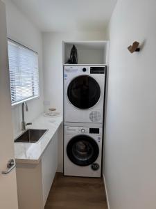 a washer and dryer in a kitchen next to a sink at The Kings Domain, DUCHESS - Luxurious townhouse in the CBD! in Blenheim