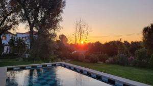 a swimming pool in a yard with the sunset in the background at Villa Cornelia, Ponte de Lima in Ponte de Lima