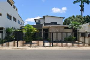 a fence in front of a building with palm trees at Acogedora suite privada en Urdesa Central, Guayaquil in Guayaquil