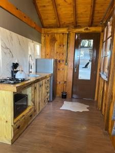a kitchen with a counter and a refrigerator and a door at Chalé Refúgio Panorâmico in Canela