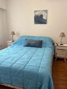 a bed with a blue comforter in a bedroom at DEPARTAMENTO MIRAMAR in Miramar