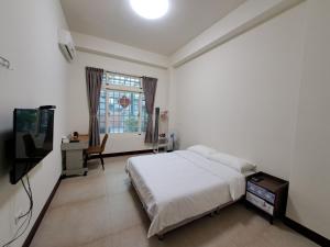 a bedroom with a bed and a desk and a television at Xinyuan Guest House in Beidou +12 photos