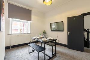 a dining room with a table and a television at Spacious 6-Bed Stay Central Warrington Sleeps 12 in Warrington