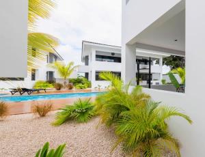 a white house with a swimming pool and palm trees at Casa di Chibi Chibi - Brand new apartment with pool close to the beach in Jan Thiel