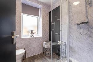 a bathroom with a shower and a toilet and a window at Spacious 6-Bed Stay Central Warrington Sleeps 12 in Warrington +33 photos