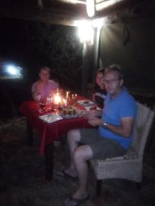 a group of people sitting at a table at night at Malombo Selous Forest Camp in Kwangwazi