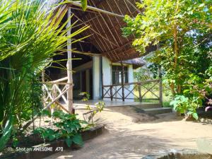 a house with a thatched roof and a porch at Malombo Selous Forest Camp in Kwangwazi