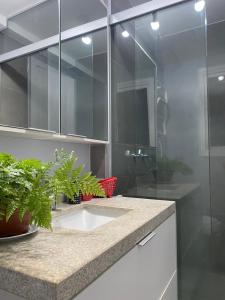 a bathroom with a sink and a glass shower at Belíssimo apartamento em Porto Alegre! in Porto Alegre