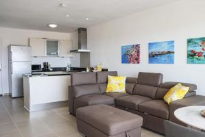 Una sala de estar con un sofá y una cocina. en Little Dreams, en Dorp Sint Michiel