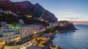 a city with buildings and the ocean at night at Relais Maresca Luxury Small Hotel & Terrace Restaurant in Capri