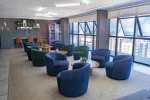 a waiting room with blue chairs and tables and windows at Edifício Time - studios em Maceió in Maceió +34 photos