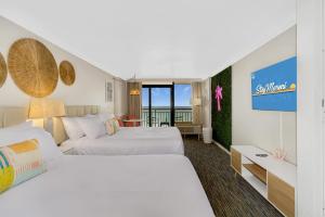 マートルビーチにあるPink Surf by StayMareni - Oceanfront 2 Queens Suiteのベッド2台とバルコニー付きのホテルの部屋