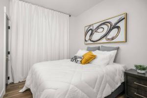 a white bedroom with a white bed with yellow pillows at Updated Family Friendly Hillyard Gem NEW HOT TUB! in Spokane