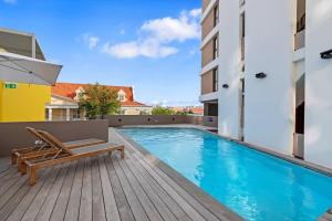 a swimming pool with a bench on a wooden deck at Island Time Retreat in Willemstad
